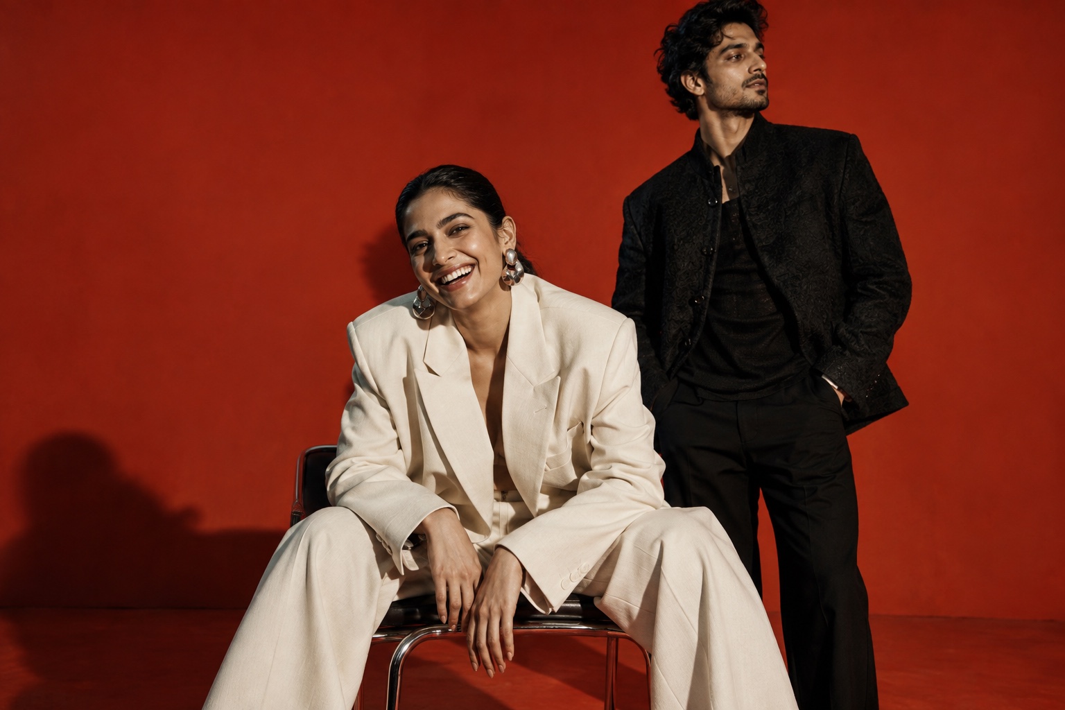 Editorial portrait of two fictional creative artists against a vermilion backdrop